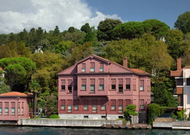 İstanbul ve Türkiye 'de yaz günü geleneksel kırmızı ev ve sık ağaçlarla, Asya yakasının yeşil dağlarından İstanbul Boğazı' ndan manzara