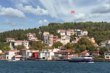 Asya yakasının yeşil dağlarından İstanbul Boğazı 'na bakın. Geleneksel evler, sık ağaçlar ve uzak uçta büyük bir Türk bayrağı var. Bir yaz günü İstanbul, Türkiye