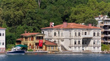 İstanbul ve Türkiye 'de yaz günlerinde geleneksel evler ve sık ağaçlarla, Asya yakasının yeşil dağlarının İstanbul Boğazı' ndan görüntüsü