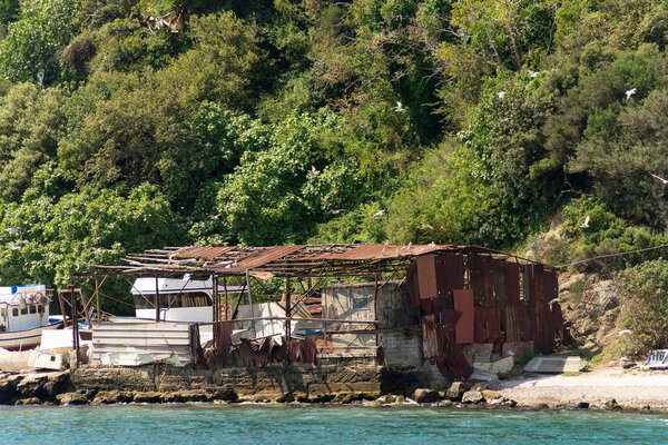 View from the sea of the green mountains of the European side of Bosphorus strait, Istanbul, Turkey, with abandoned broken wooden hut