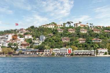 İstanbul ve Türkiye 'de yaz günlerinde geleneksel evler ve sık ağaçlarla, Asya yakasının yeşil dağlarının İstanbul Boğazı' ndan görüntüsü