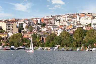 Güneşli bir yaz gününde, İstanbul, Türkiye 'de Haliç' in kıyılarına yanaşan tekneler, yoğun ağaçlar ve konut evleri ile yeşil parkın arka planına sahipti.