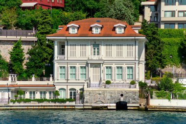 İstanbul ve Türkiye 'de yaz günlerinde geleneksel evler ve sık ağaçlarla, Asya yakasının yeşil dağlarının İstanbul Boğazı' ndan görüntüsü