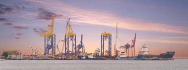 Türkiye 'nin İstanbul, Haydarpaşa Limanı üzerinde güzel bir gün doğumu, kargo gemileri ve vinçler gökyüzüne karşı. Su gündoğumunun renklerini yansıtır, canlı ve enerjik bir sahne yaratır.