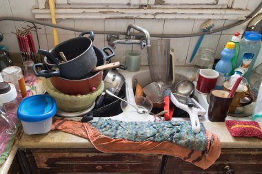 Close-up photo of a messy kitchen sink filled with dirty high piled dishes and utensils clipart