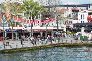 İstanbul, Türkiye - 8 Mayıs 2023: Ortakoy Meydanı, İstanbul Boğazı 'nda yayaların yürüyüş yaptığı ve anıt fotoğrafları çektiği popüler bir turizm beldesi. Boğaz köprüsü uzak uçta görünüyor
