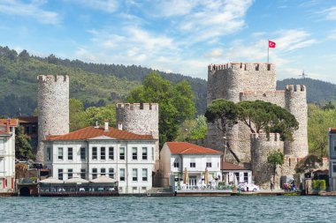 İstanbul, Türkiye - 8 Mayıs 2023: Anadoluhisari Kalesi ile İstanbul Boğazı 'nın Asyalı tarafının görüntüsü, arka planda Osmanlı Sultanı I. Bayezid tarafından inşa edilmiş, yeşil dağlı bir kale.