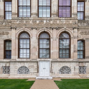 Dolmabahce Sarayı 'nın yan duvarı, küçük ahşap kapılı ve kemerli pencereli. İstanbul, İstanbul, Türkiye 'nin Avrupa kıyılarındaki Beşiktaş ilçesinde yer alan saray