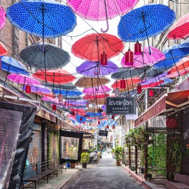 İstanbul, Türkiye - 13 Mayıs 2023: Karaköy 'de bir ara sokakta asılı renkli şemsiyelerden oluşan canlı bir tepe örtüsü, kaprisli ve eğlenceli bir atmosfer yaratan göz alıcı bir tesiste asılı duruyor