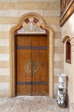 Yıpranmış kemerli Mamluk mimari tarzı ahşap kapılı, eskimiş taş bir duvara yerleştirilmiş.