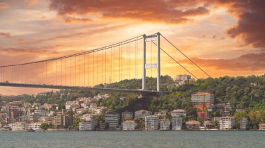 Günbatımının altın renklerinde yıkanan Boğaz Köprüsü, aşağıdaki İstanbul ve Türkiye 'nin ışıldayan sularına büyüleyici bir yansıma sergiliyor.