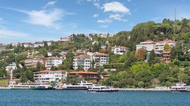 Bebek, View from the sea of the green mountains of the Europian side of Bosphorus strait, with docked boats, traditional houses and dense trees in a summer day, Istanbul, Turkey 