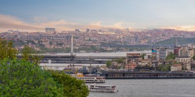 İstanbul 'un Avrupa yakasının panoramik ufuk çizgisi, İstanbul, Türkiye' de güneş batmadan bir bahar önce Halic Metro Köprüsü 'ne bakan feribot tekneleri ile İstanbul' un İstanbul, Türkiye