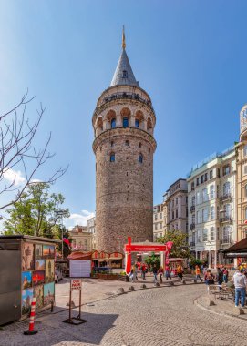 İstanbul, Türkiye - 13 Mayıs 2023: Ortaçağ Galata Kulesi etrafındaki turistler ve açık mavi gökyüzü