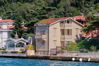 İstanbul ve Türkiye 'de yaz günlerinde geleneksel evler ve sık ağaçlarla, Asya yakasının yeşil dağlarının İstanbul Boğazı' ndan görüntüsü