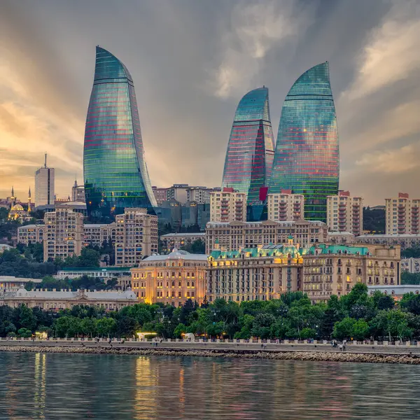 stock image Night view of the iconic illuminated Flame Towers in Baku, Azerbaijan, The modern architecture of the buildings is reflected in the calm waters of the Caspian Sea