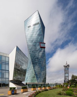 Bakü Emlak Kulesi: Azerbaycan 'da güneşli bir bahar gününde mavi gökyüzüne karşı çarpık bir tasarımı olan modern bir gökdelen