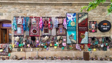 Baku, Azerbaijan - May 4 2024: A shop in the historic Icherisheher district of Baku, showcasing colorful woven rugs, bags, and other traditional goods for sale clipart