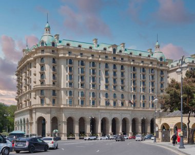 Baku, Azerbaijan - May 10, 2024: Beaux-Arts style Four Seasons Hotel stands on Neftchiler Avenue street. The building features a symmetrical facade with multiple stories, arched windows, and domes clipart