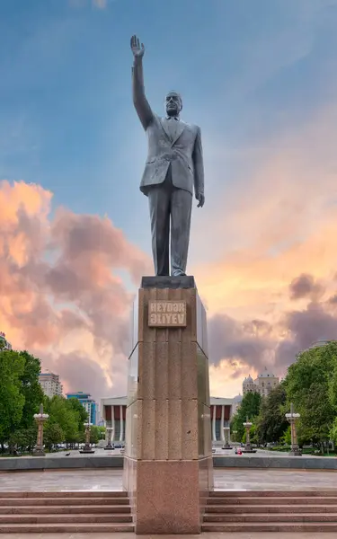stock image Brass statue of Heydar Aliyev in Baku, Azerbaijan, dedicated to the former Azerbaijani President, in Heydar Aliyev Square against vibrant sunset, in front of a palace that bears the president name