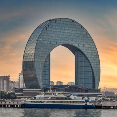 Gün batımında Bakü, Azerbaycan 'da kendine özgü Crescent Binası çerçeveli, limana demirlemiş lüks bir yatın huzurlu manzarası.