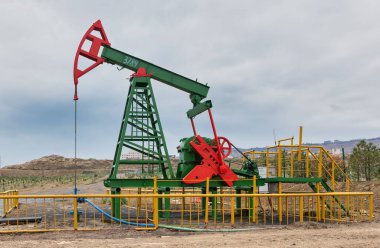Yeşil ve kırmızıya boyanmış, sarı çitlerle çevrili, Bakü, Azerbaycan 'da bulutlu bir gökyüzüne kurulmuş operasyonel bir benzin pompası.