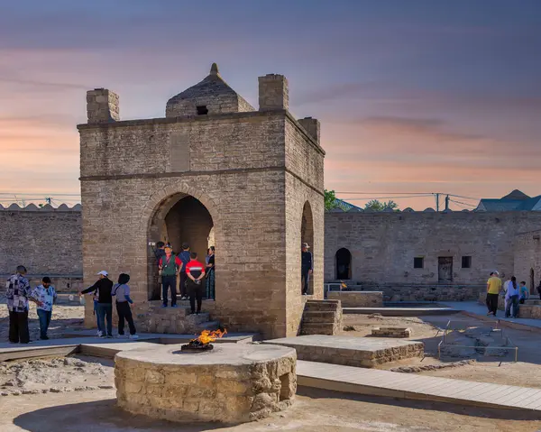 stock image Baku, Azerbaijan - May 9, 2024: Tourists gather in the courtyard of the ancient Ateshgah Fire Temple, in the historical architecture during sunset