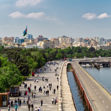 Bakü, Azerbaycan - 4 Mayıs 2024: İnsanlar Bakü Bulvarı boyunca yürüyüp, temiz hava ve deniz manzarasının ve berrak bir gökyüzü altında canlı şehir manzarasının tadını çıkarıyorlar.