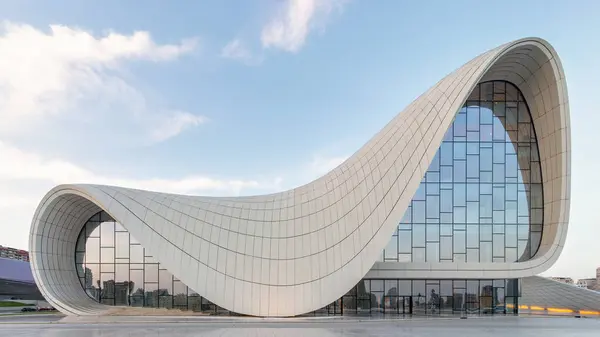 stock image The iconic Heydar Aliyev Centre in Baku, Azerbaijan, showcases modern architecture with its fluid, wave-like design against a blue sky. Building designed by the deceased architect Zaha Hadid 