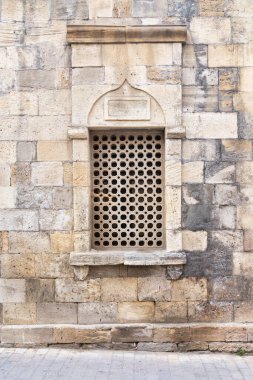 Tarihi bir yapının çarpıcı bir özelliği, geçmişten gelen uzman işçiliğini ön plana çıkaran, dayanıklı taş bir duvara yerleştirilmiş geometrik desenle süslenmiş güzel hazırlanmış bir pencereyi gözler önüne seriyor.