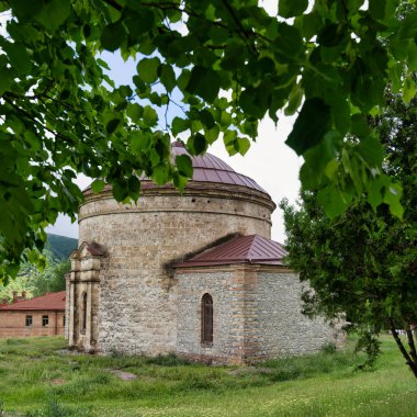 The Round Temple, also known as Three Saints Church, situated amidst verdant landscapes and mountains in Shaki, Azerbaijan clipart