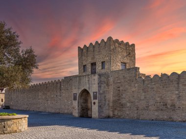 Gün batımında, Ateshgah 'ın Bakü, Azerbaycan' daki Ateshgah Ateş Tapınağı 'nın girişi, tarihi bir Zoroastrian sahası, kemerli bir kapısı ve küçük pencereli bir kulesi olan taş bir yapı sergiliyor.