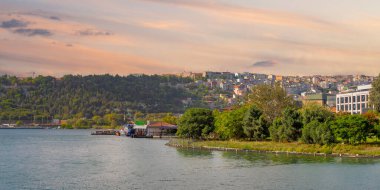 Günbatımında parlayan Altın Boynuz, canlı yeşillikler ve İstanbul, Türkiye 'de Beyoğlu' nun hareketli kentsel yaşamı ile çevrili, şehirlerin zengin tarihi ve doğal güzelliğini yansıtıyor.