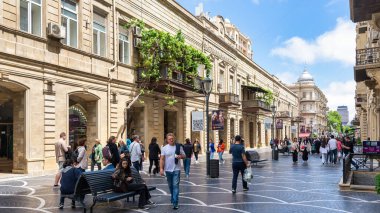 Bakü, Azerbaycan - 5 Mayıs 2024: Nizami Caddesi yayalar açık mavi gökyüzü altında yürürken hareketlilik ile doludur. Yeşillik, balkonları süsler ve canlı atmosferi güçlendirir.