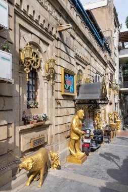 Baku, Azerbaijan - May 6, 2024: Historic Tazabay Hamami, Bathhouse facade, features intricate architecture, golden sculptures, and decorative elements and colorful art in a lively alleyway clipart