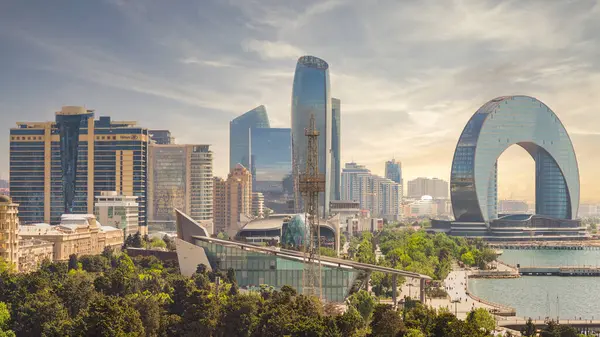 Bakü, Azerbaycan - 10 Mayıs 2024: Paraşüt Kulesi, Hilal Geliştirme Projesi, Hilton ve Absheron otelleri, canlı bir günbatımına karşı, günbatımına karşı, liman kıyısında modern mimari ile ufuk çizgisini yakalıyor