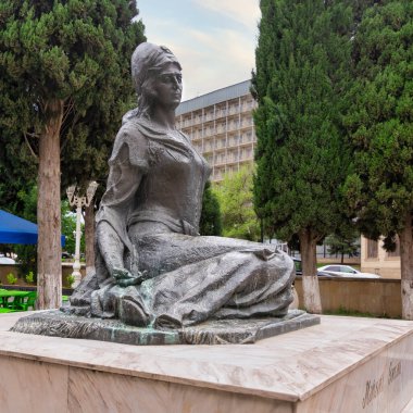 A statue of the esteemed 12th-century Azerbaijani poet Mahsati Ganjavi is elegantly situated, surrounded by verdant trees and outdoor seating in Shaki, Azerbaijan clipart