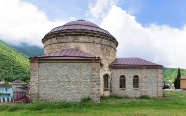 The Three Saints Church, also known as The Round Temple, is nestled amidst verdant landscapes and mist-covered mountains in Shaki, Azerbaijan near the Khans palace clipart