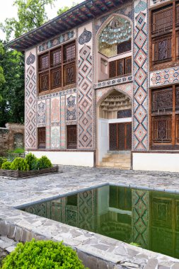 The intricate architecture of Shaki Khan Palace, situated in Shaki, Azerbaijan, surrounded by lush greenery and a tranquil reflection pool clipart