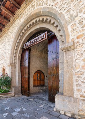 Upper Caravanserai in Shaki features a beautiful stone entrance with wooden doors. This historic site reflects the architectural style of the region, inviting exploration of its rich history clipart