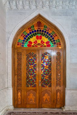 Karmaşık boyalı camlar Bibi-Heybat Camii, Bakü, Azerbaycan 'da ahşap bir kapı dekore ediyor, canlı renkler ve ayrıntılı desenler sergiliyor, zengin kültür mirası ve mimari zarafeti yansıtıyor.