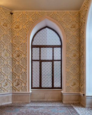 Ganja, Azerbaycan 'daki İmazade Camii' nin içinde, karmaşık desenler ve İslami sanat ve mimariyi yansıtan renkli bir halı ile güzel tasarlanmış kemerli bir pencere bulunuyor.