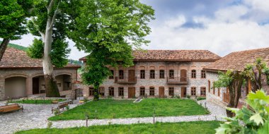 Shaki Hans Cami Kompleksi 'nin dışı, Shaki, Azerbaycan' da tarihi bir yapı, taş duvarlar, ahşap balkonlar ve geleneksel mimari unsurlar sergileniyor.