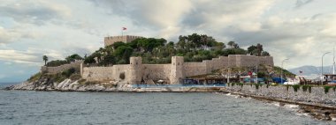 Türkiye 'nin Aydın ilinde yer alan Kusadasi Şatosu, yemyeşil ve engebeli kıyı şeritleriyle çevrili görkemli bir tepenin üzerinde bulunuyor. Dalgalar tahkimatlara hafifçe çarpar