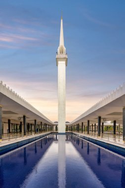 Malezya Ulusal Mescidi 'nin çarpıcı minaresi Kuala Lumpur' da güneş batarken sakin su yansımalarının arasında dimdik ayakta duruyor.