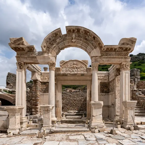 Efes, Seluk, İzmir, Türkiye 'deki Hadrian Tapınağı, tarihi kalıntılarla çevrili karmaşık mimariyi gözler önüne seriyor. Yapı dramatik bir gökyüzüne karşı görkemli bir şekilde duruyor.