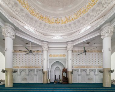 Kuala Lumpur, Malezya 'daki El-Buhari Vakfı Camii' nin iç mimarisi, beyaz sütunlar, altın Arap kaligrafisi, karmaşık bir kubbe tavanı, bir mihrab, bir minbar ve yeşil bir dua halısına sahip.