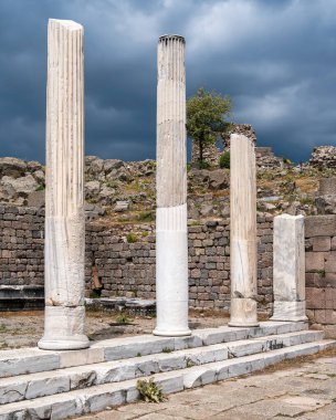 Türkiye 'nin Pergamon, Bergama kentindeki Trajan harabelerindeki Antik sütunlar kara bulutlu gökyüzü altında.