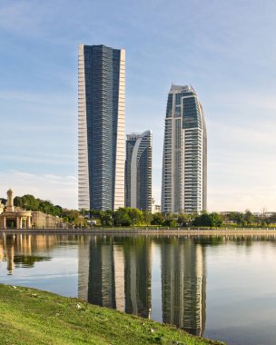 Putrajaya, Malezya - 20 Şubat 2025::: Putrajaya Gölü 'ndeki Seri Gemilang Köprüsü, Menara Usahawan, KKDW ve KPKT hükümet binalarının bir yansıması