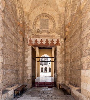 Kahire 'deki Al-Zahir Baybar Camii' nin yan girişinin ayrıntılı taş işçiliği ve kemerleri. Tarihi mekanda İslam mimarisi sergileniyor, zengin mirası üzerinde keşif ve yansımaya davet ediliyor.
